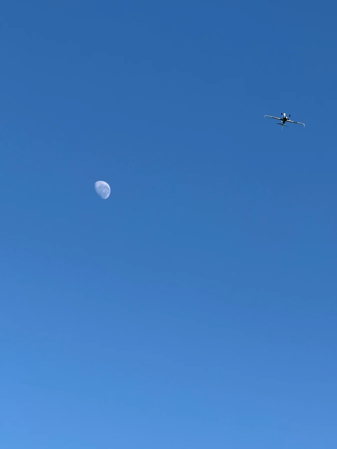 The race aircraft high in a blue sky above the visible moon