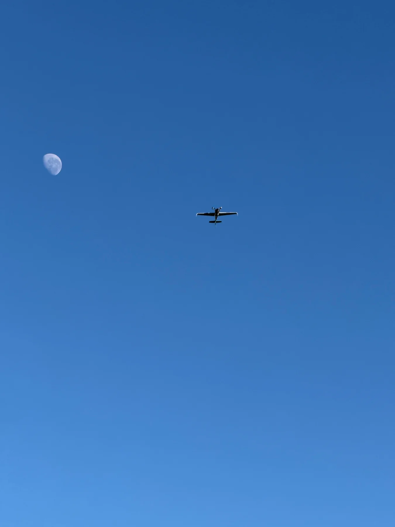 The Edge 540 flying against blue sky with the moon below