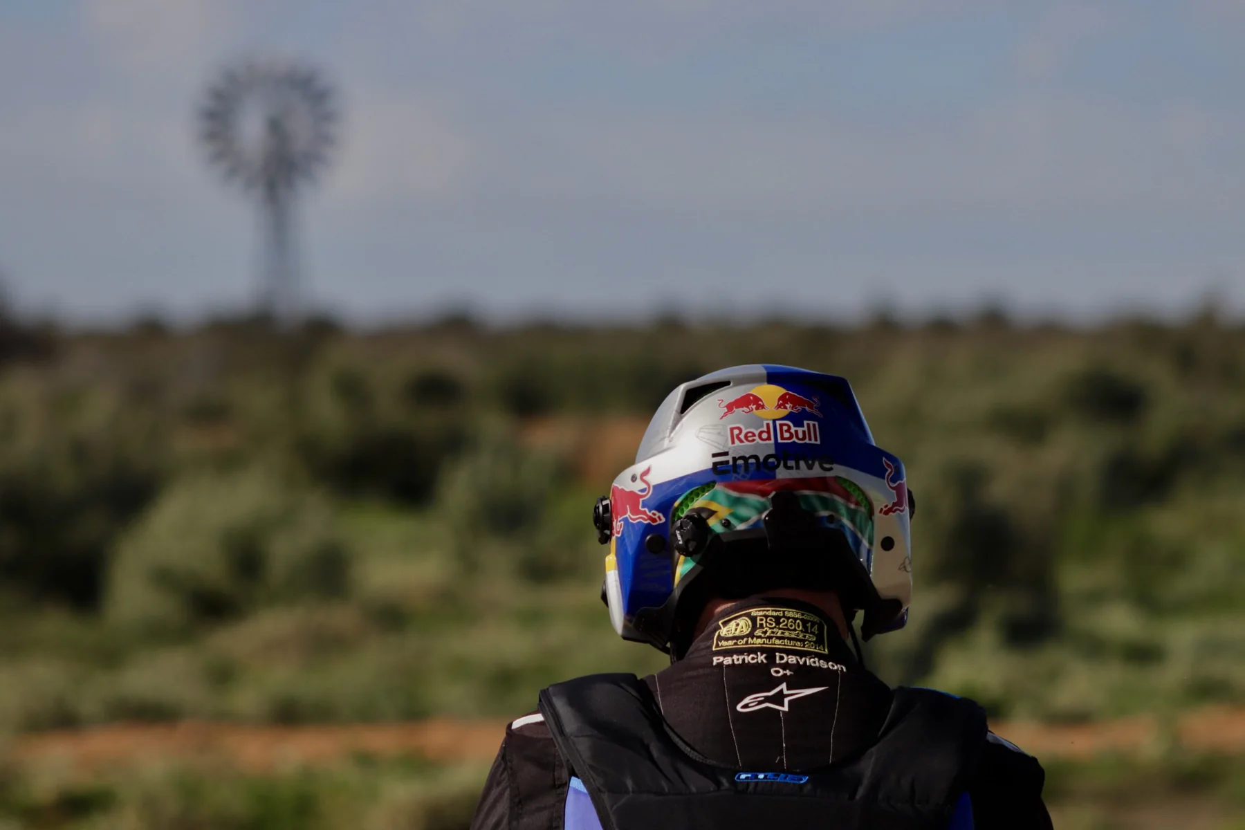Rear view of Patrick Davidson in flying gear, with Red Bull and Emotive branding on his helmet.