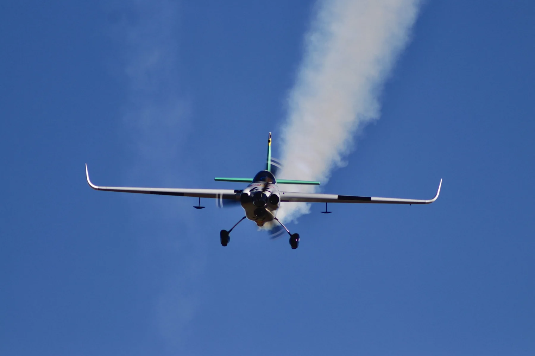 Head-on view of Patrick Davidson’s Emotive-liveried number 77 race aircraft in flight with a smoke trail.
